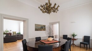 A spacious dining area with a round table, six chairs, and a chandelier. - Dimora Torremuzza historic home downtown Palermo with three bedrooms and 4 bathrooms (Palermo)