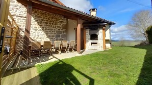 A stone building with a fireplace, outdoor seating, and a grassy yard. - Gîte du Platane, Sleeps 14 (Grazac)