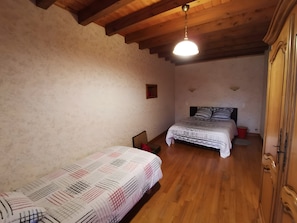 A bedroom with two beds, wooden flooring, a wooden ceiling, and a hanging light fixture. - Gîte du Platane, Sleeps 14 (Grazac)