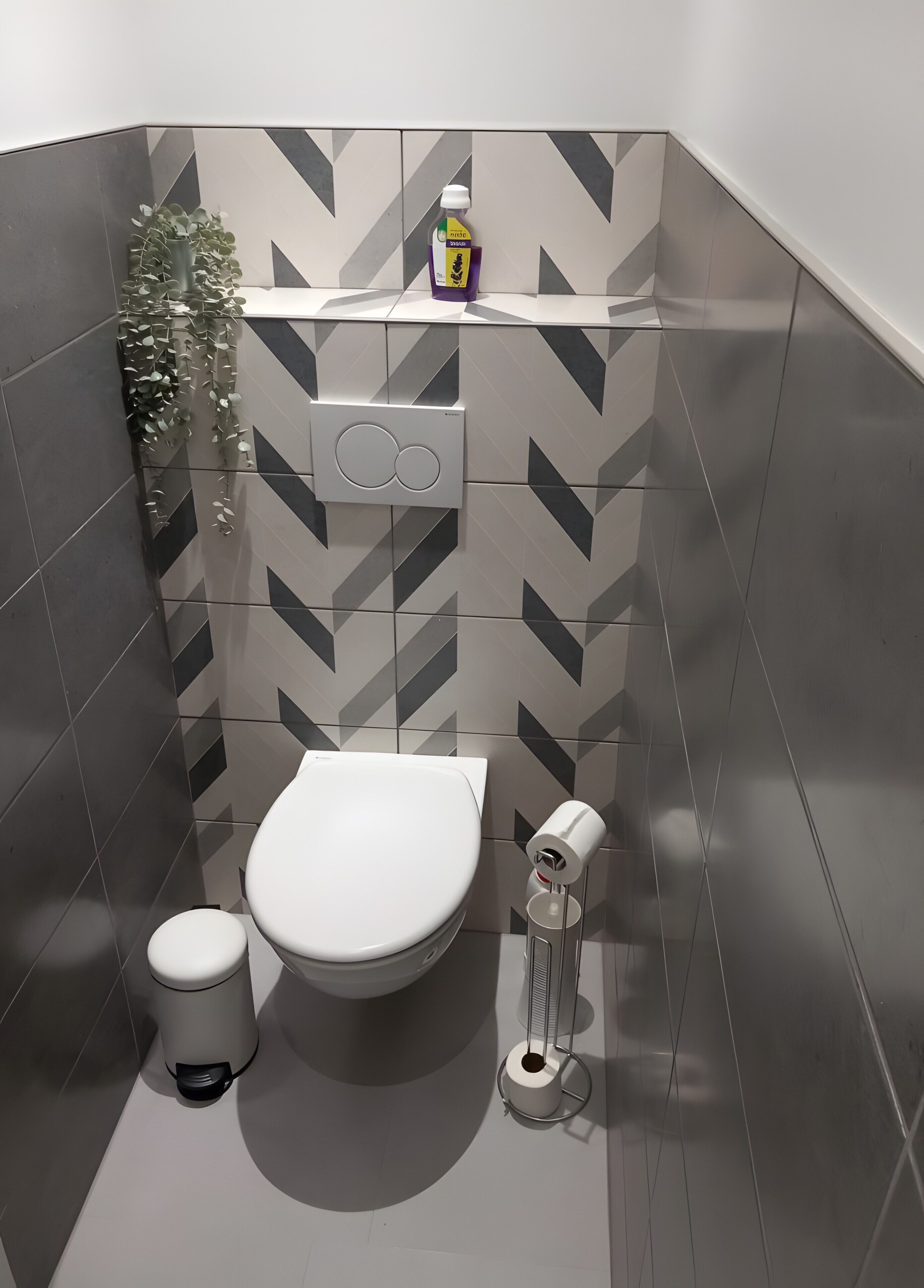 A modern bathroom with a toilet, bidet, and a wall-mounted toilet paper holder.