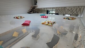 Una habitación amplia con techo alto, una escalera y una cama grande con dosel blanco.