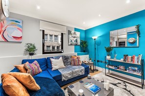 Un salon moderne avec un canapé bleu, une table basse et une bibliothèque.