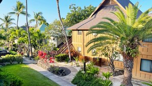 A tropical resort with a well-maintained garden, palm trees, and a two-story building with a sloped roof. - Gorgeous 2 bdrm presidential unit (Kailua-Kona)