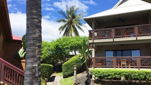 A two-story building with a balcony, surrounded by lush greenery and a palm tree. - Gorgeous 2 bdrm presidential unit (Kailua-Kona)