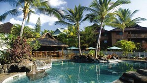 A resort pool with palm trees, a thatched-roof hut, and a building with balconies. - Gorgeous 2 bdrm presidential unit (Kailua-Kona)