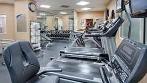 Een fitnessruimte met loopbanden, gewichten en trainingsapparatuur.