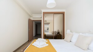 Une chambre d’hôtel avec un lit, un couvre-lit jaune, une porte en bois et un plafond blanc.