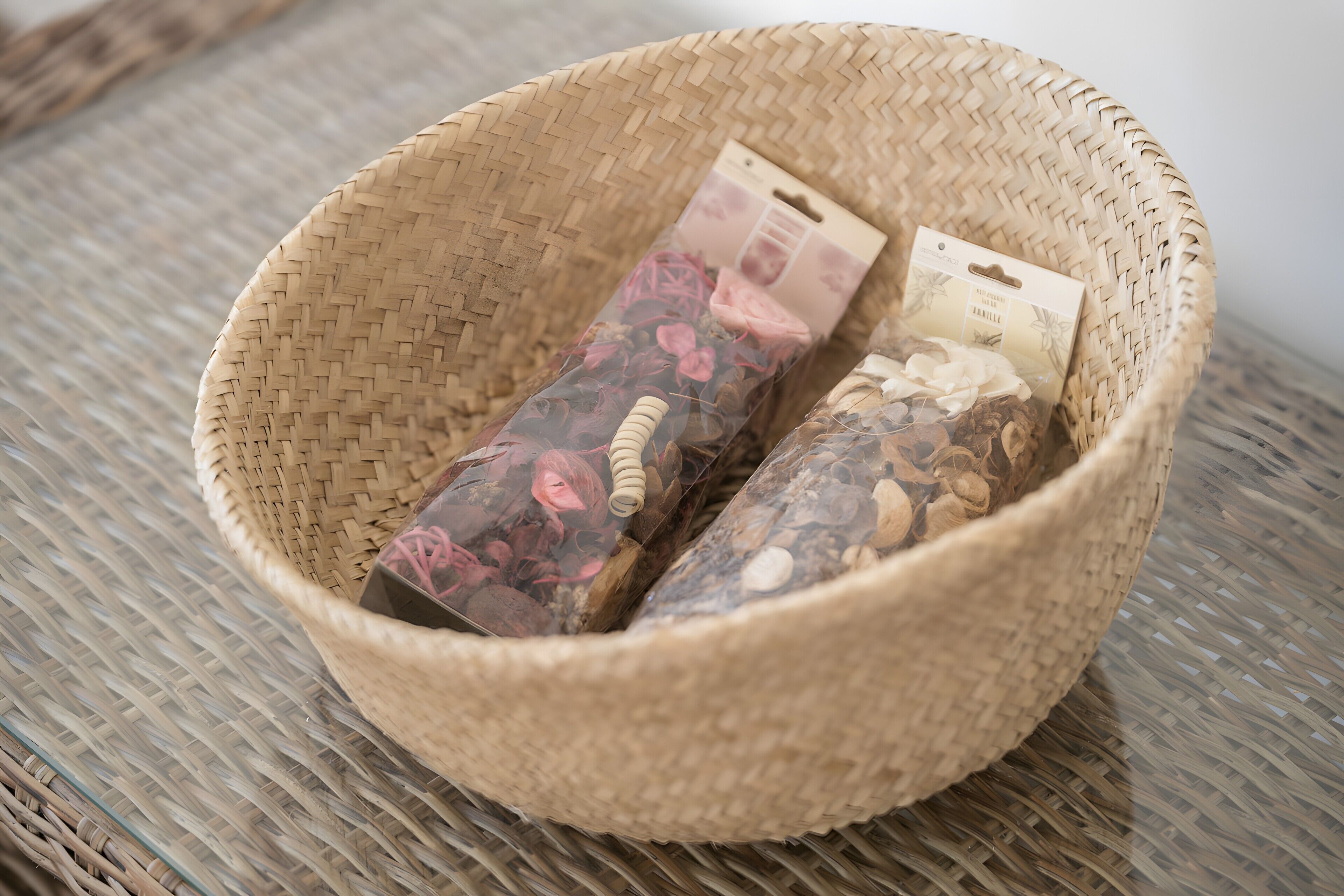 Un panier tressé contenant des fleurs séchées et une boîte étiquetée « Santal et vanille ».