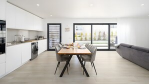 Una cocina moderna con comedor, lavadora y un sofá gris.
