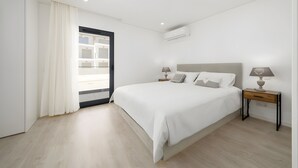 Un dormitorio moderno con una cama grande, mesitas de noche y una ventana con cortinas.
