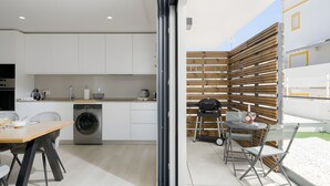Una cocina moderna con electrodomésticos integrados, un comedor con mesa y sillas, y vistas al exterior.