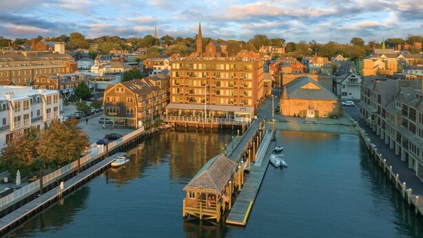 A waterfront hotel with a dock, a church spire, and a mix of residential buildings. - Inn on the Harbor resort (Newport)