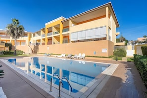 A multi-story hotel with a swimming pool, sun loungers, and a clear blue sky. - Entire Apartment in Guia, Portugal (Guia)