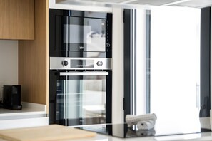 Eine moderne Küche mit Einbauofen und Mikrowelle, einer Kaffeemaschine und einem Kühl- und Gefrierschrank mit Glastür.