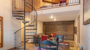 A dining area with a wooden table, chairs, and a spiral staircase. - Hotel Spa le Suisse  (Saint-Donat-de-Montcalm)