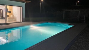 A swimming pool with clear water, surrounded by a paved area and a building with a tiled roof. - Enjoy our heated swimming pool, both in summer and winter. (Ponte de Lima)