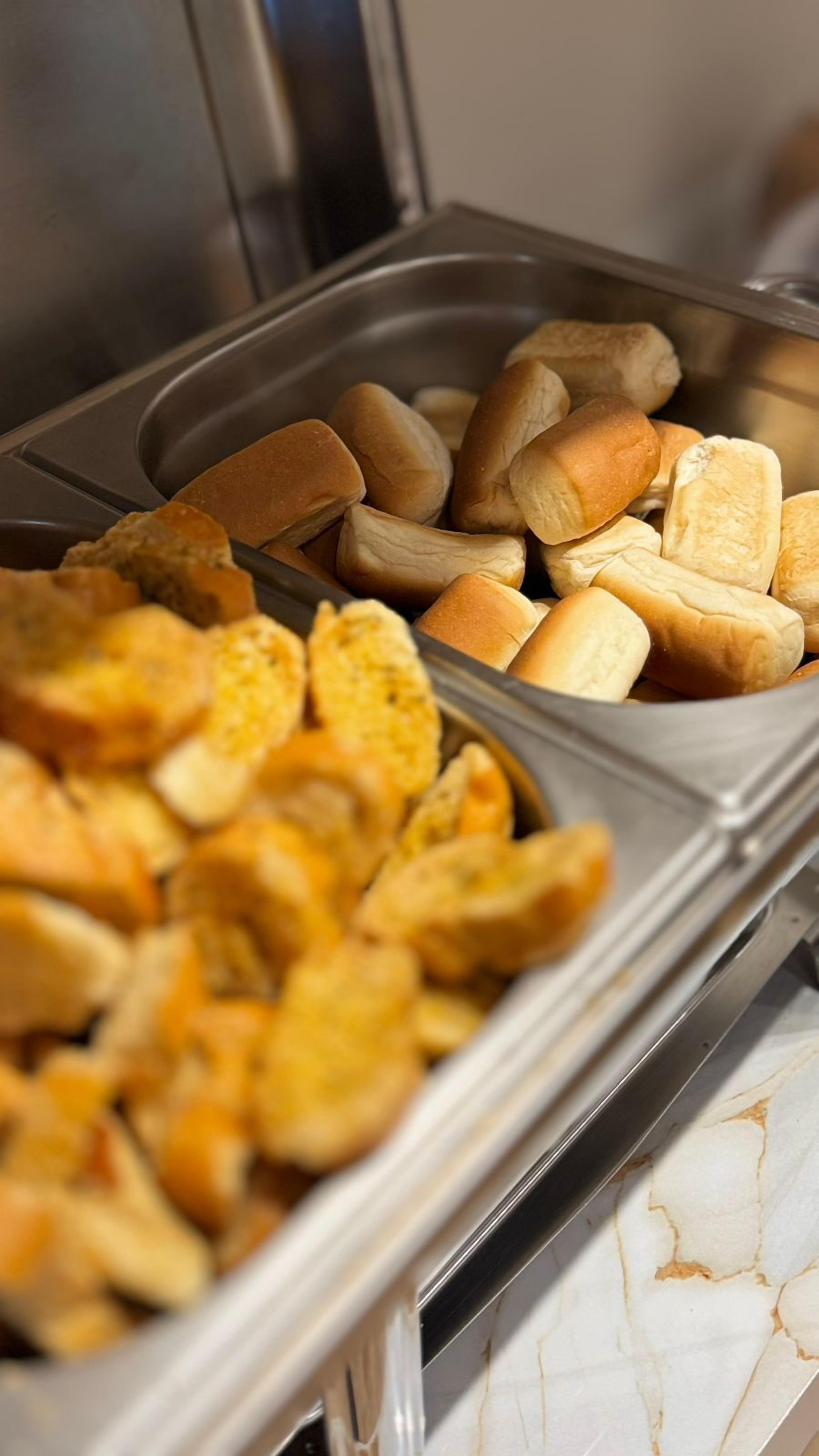 A buffet with various food items including bread rolls and fried items.