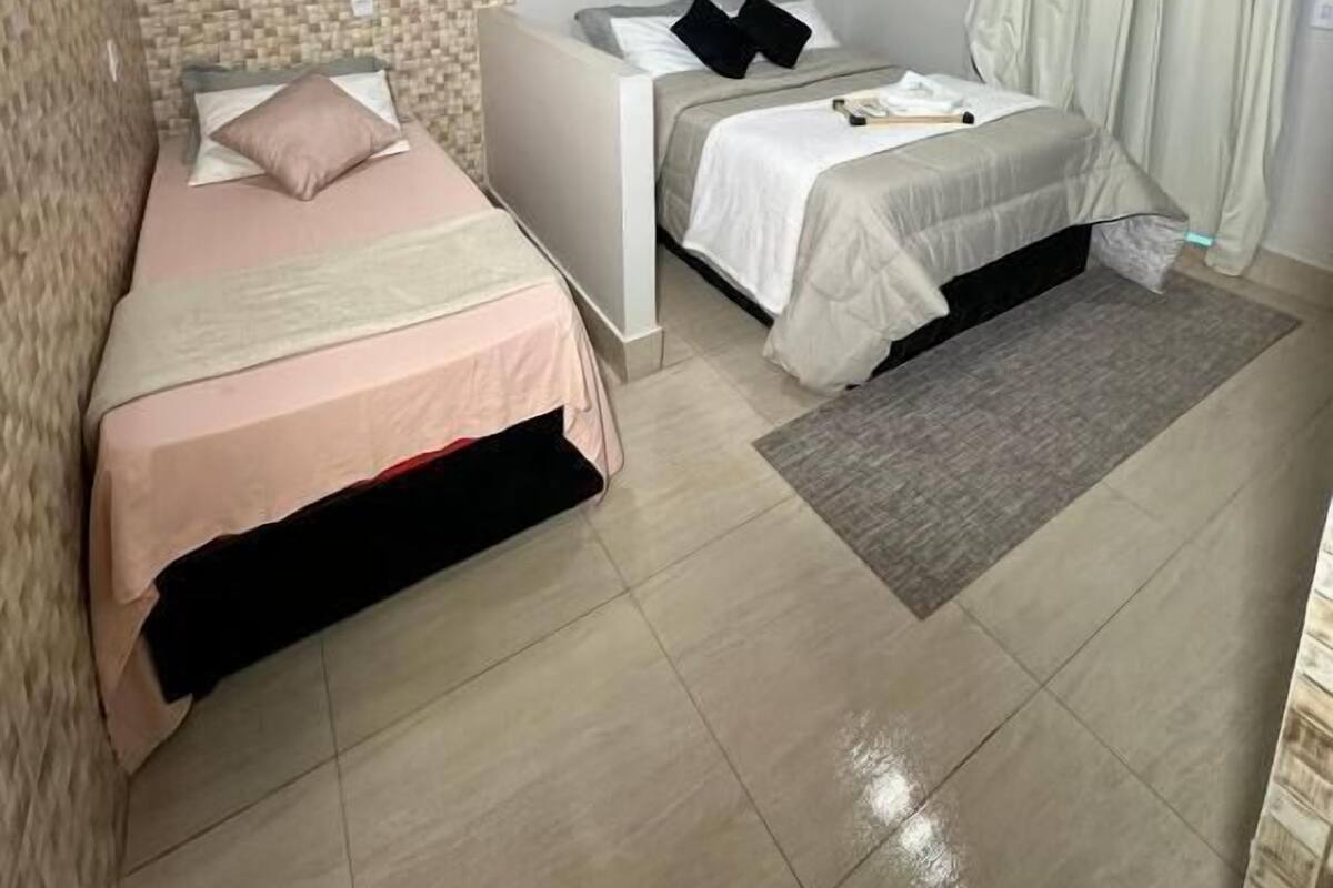 Un dormitorio moderno con dos camas, una obra de arte circular grande en la pared y un tapete gris.