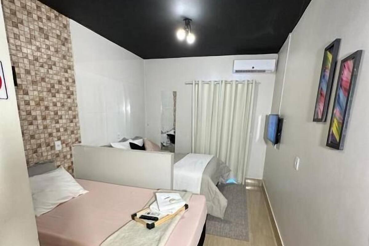 Una habitación de hotel pequeña con cama, un escritorio, un espejo y una ventana con cortinas.