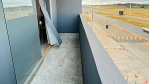 Un balcón con vista a una pista de aterrizaje y edificios del aeropuerto.