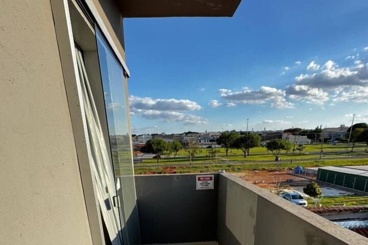 Un balcón estrecho con vistas a una zona residencial, cielo despejado y un letrero que indica un área de estacionamiento.