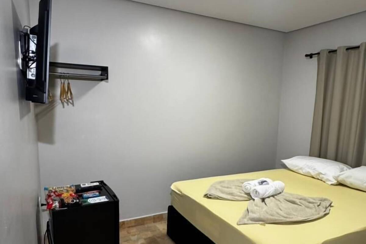 Una habitación de hotel con cama, televisor, una mesita con aperitivos y suelo de baldosas.