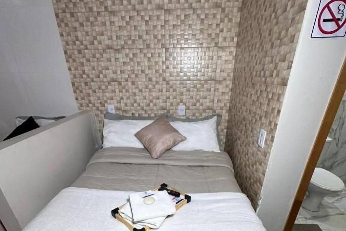 Una cama bien hecha con un cubrecolcha acolchado, una almohada y una toalla doblada sobre la cama.
