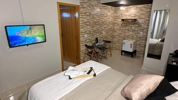 Un dormitorio con cama, televisión en la pared, escritorio y armario.
