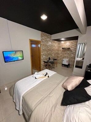 A bedroom with a bed, a TV on the wall, a desk, and a wardrobe. - RIACHO HOTEL (Riacho Fundo II)