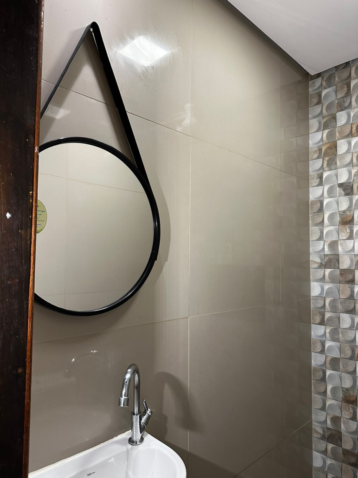 A bathroom with a white sink, a modern faucet, and a mirror with a black frame.