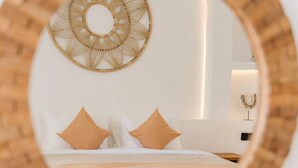 Une chambre à coucher avec un lit, deux oreillers, un objet décoratif fixé au mur et une table de chevet sur laquelle se trouve un petit objet.
