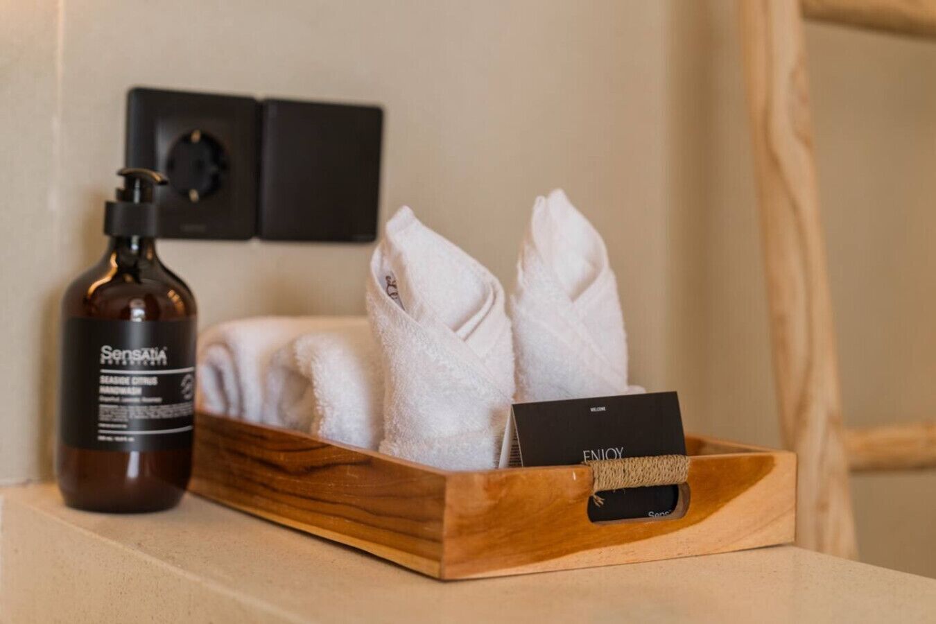 Una bandeja de madera con dos toallas blancas y una botella de Jabón de Manos Sensatia Marine Citrus.