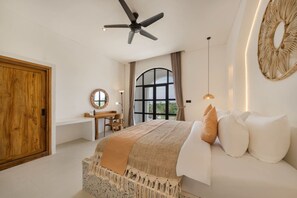 A bedroom with a large bed, a desk, and a window with a view.