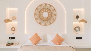 Une chambre moderne avec un luminaire circulaire fixé au centre du mur, des tables de chevet ornées d’objets décoratifs et un lit avec deux oreillers.