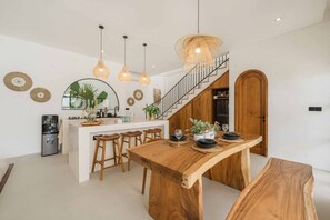 A modern kitchen with a central island, wooden bar stools, and pendant lighting. - 2BR Private Pool Villa w/ Sunset Rooftop Ungasan (South Kuta)