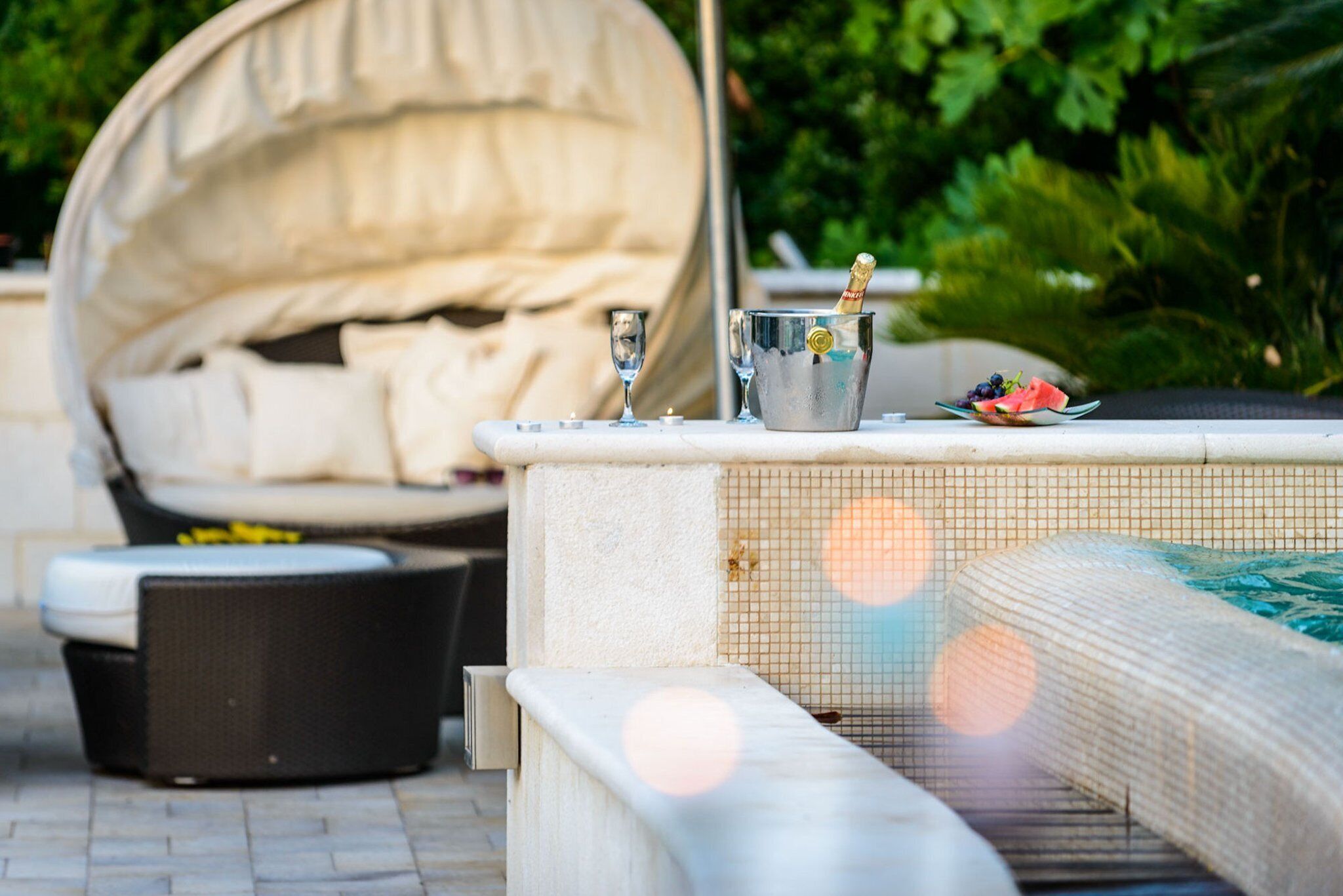 An outdoor seating area with a covered sofa, a pool table, and a hot tub.