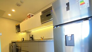 Una cocina moderna con electrodomésticos de acero inoxidable, incluyendo un refrigerador y una lavadora, además de un microondas sobre el horno.