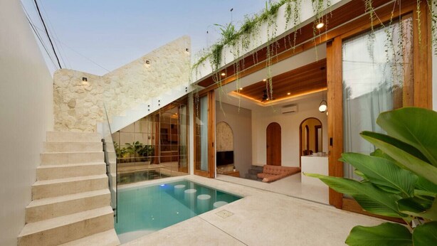 A modern pool area with a stone staircase, a glass-enclosed lounge, and wooden beams. - Modern 1BR Oasis - Sunken Lounge & Near Canggu (Mengwi)
