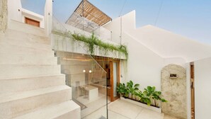 A modern interior with a glass staircase, a wooden door, and a stone wall. - Modern 1BR Oasis - Sunken Lounge & Near Canggu (Mengwi)