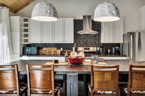 Una cocina moderna con una isla central, armarios blancos y salpicadero negro.
