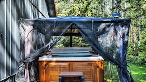 A hot tub with a wooden deck and a bench, surrounded by a covered area with a metal wall. - Aspen Acre @ Pigeon Lake Hot Tub Fire Pit StarLink (Poplar Bay)
