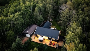 A modern house with a large deck, surrounded by dense forest. - Aspen Acre @ Pigeon Lake Hot Tub Fire Pit StarLink (Poplar Bay)
