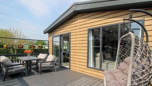 A deck with outdoor furniture, a hanging chair, and a glass door leading to an interior space. - Poppy (Leominster)