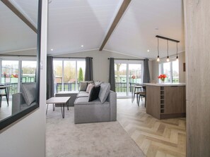 Una sala de estar moderna con un sofá gris, una mesita y una zona de cocina con barra.