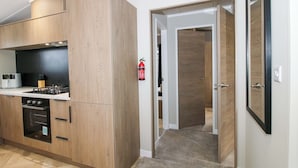 A modern kitchen with wooden cabinets, a stove, and a fire extinguisher. - Poppy (Leominster)