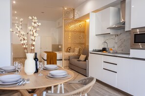 Uma cozinha moderna com armários brancos, forno embutido e micro-ondas.