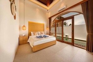 Een ruime slaapkamer met een groot bed, een houten hoofdbord, een nachtkastje, een hanglamp en een schuifdeur naar een buitenruimte.