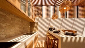 A modern kitchen with a stone wall, wooden counter, and a dining area with stools. - Stylish 2BR Villa near Central Ubud (Ubud)