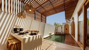 A sunlit outdoor dining area with a pool, wooden furniture, and a pergola overhead. - Stylish 2BR Villa near Central Ubud (Ubud)