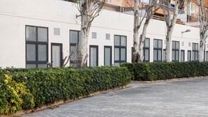 Un sendero pavimentado con una hilera de edificios blancos, cada uno con varias ventanas y una puerta.